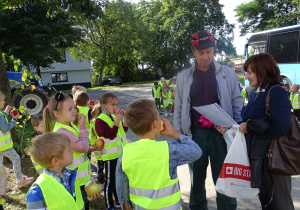 Dzieci wraz z panią wręczają podziękowania za możliwość poznania pracy sadownika oraz skosztowanie pysznych jabłek