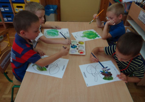 Chłopcy malują farbami obrazek przedstawiający jabłko