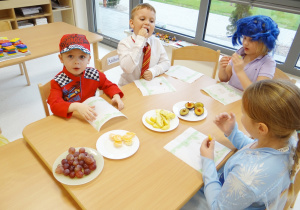 Dzieci jedzą urodzinowe owoce od Zuzi.