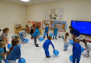Dzieci bawią się przy muzyce z balonami, w kolorze niebieskim.