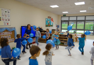 Dzieci biegają z niebieskimi balonami.