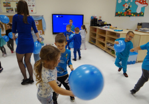 Dzieci tańczą w parach z niebieskim balonami.