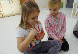 Zuzia słucha bicia swojego serca przy pomocy stetoskopu.