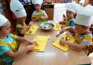Dzieci kroją różne owoc e na sałatkę