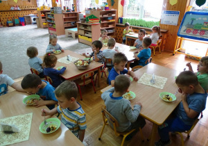 Dzieci jedzą włsasnoręcznie przygotowaną sałatkę owocową