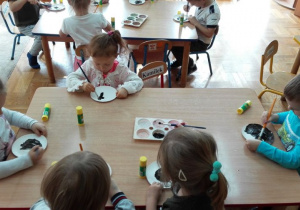 Dzieci malują farbami po talerzykach paierowych
