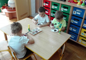Chłopcy zamalowują talerzyk papierowy