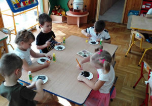 Dzieci malują na czarno paierowe talerzyki