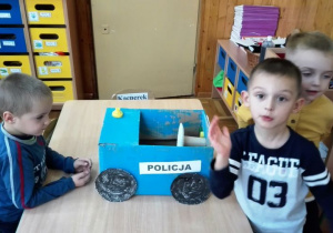 Chłopcy ozdabiają radiowóz z kartonu