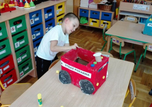 Chłopczyk robi wóz strażacki z kartonu