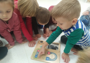 Dzieci oglądają pomoc z magnesami.