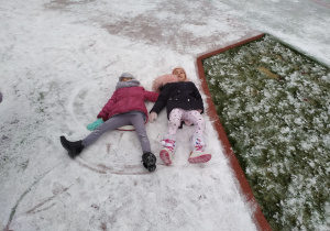 Nadia i Ola robią orły na śniegu.