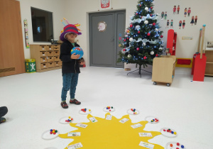 Igor stoi w urodzinowym kapeluszu przy słoneczku z globusem.