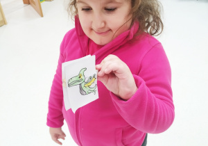 Zuzia pokazuje swojego dinozaura na spinaczu.