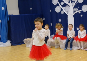 Lenka stoi na środku i składa życzenia w języku migowym.