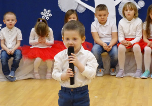 Adaś stoi na środku sali recytując swój wierszyk.