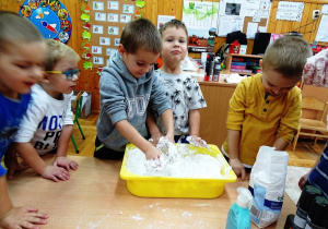 Dzieci mieszaja piankę z mąką i mydłem w płynie