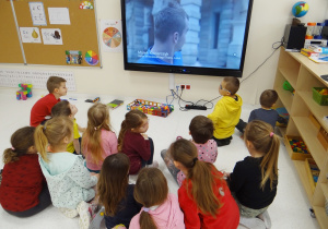 Żabki siedzą przed monitorem i oglądają film o teatrze.