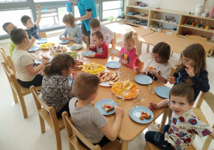 Dzieci siedzą przy stole nad owocową ucztą.
