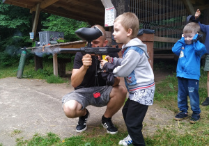 Skupiony Mariuszek celuje w tarczę z pistoletu do paintballa.