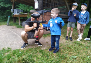 Zadowolony Adaś strzela z pistoletu do paintballa.