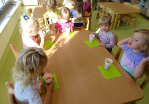 Dzieci piją sok przy stolikach