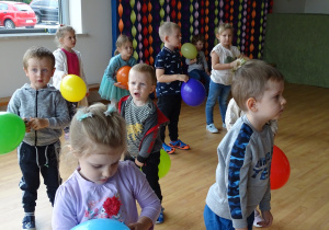 Dzieci stoją z kolorowymi balonami.