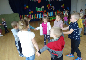 Dzieci z 3-4-latków tańczą w kole trzymając się za ręce.