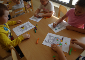 Dzieci wyklejają kropkami plasteliny sowę