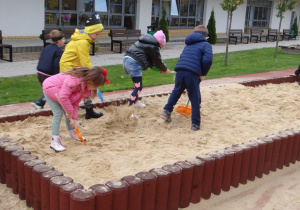 Dzieci kopią łopatkami w piaskownicy