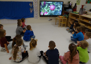 Dzieci oglądają filmik o owocach na tablecie w sali