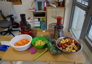 Wyciskarka, sokowirówka i przygotowane składniki na stoliku