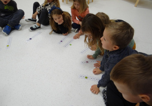 Dzieci układają guziki na planszy z cyframi