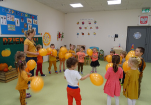 Dzieci tańczą z pomarańczowymi balonami