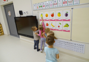 Dzieci dopasowują swoje małe obrazki do obrazków owoców znajdujących się na tablicy.