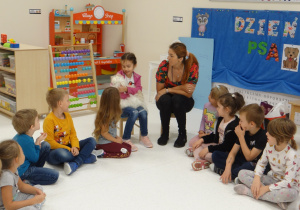 Dzieci w kółeczku słuchają informacji o piesku