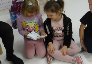 Dziewczynki oglądają książeczkę zdrowia pieska