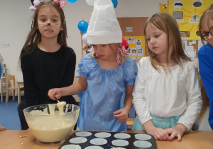 Dziewczynki nalewają ciasto do foremek.