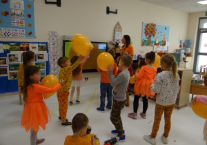 Dzieci z pomarańczowymi balonami w ręku