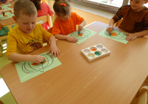 Dzieci ozdabiają dynie pomarańczową farbą