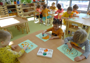 Dzieci pracują za pomocą gąbeczek, kolorują dynie