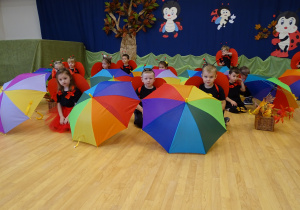 Dzieci kucają koło parasoli