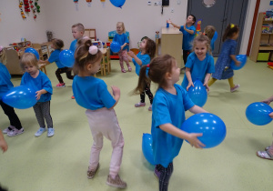 Dzieci tańczą z niebieskimi balonami