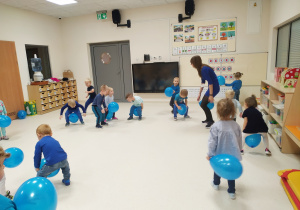 Maluchy bawią się niebieskimi balonami - chodzą z nimi między nogami.