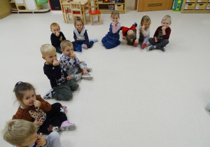 Dzieci siedzą na podłodze i pokazują swoje nosy.