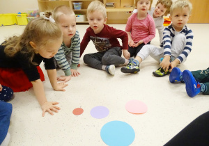 Dzieci siedzą na podłodze i oglądają rozłożone przed nimi koła w różnych rozmiarach.