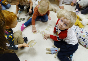 Dzieci siedzą na podłodze i układają misie.