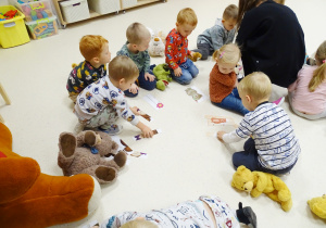 Dzieci układają na podłodze obrazki pluszowych misiów.