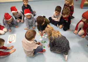 Dzieci układają puzzle przedstawiające Św. Mikołaja