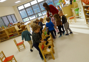 Dzieci stoją wokół krzesełek.